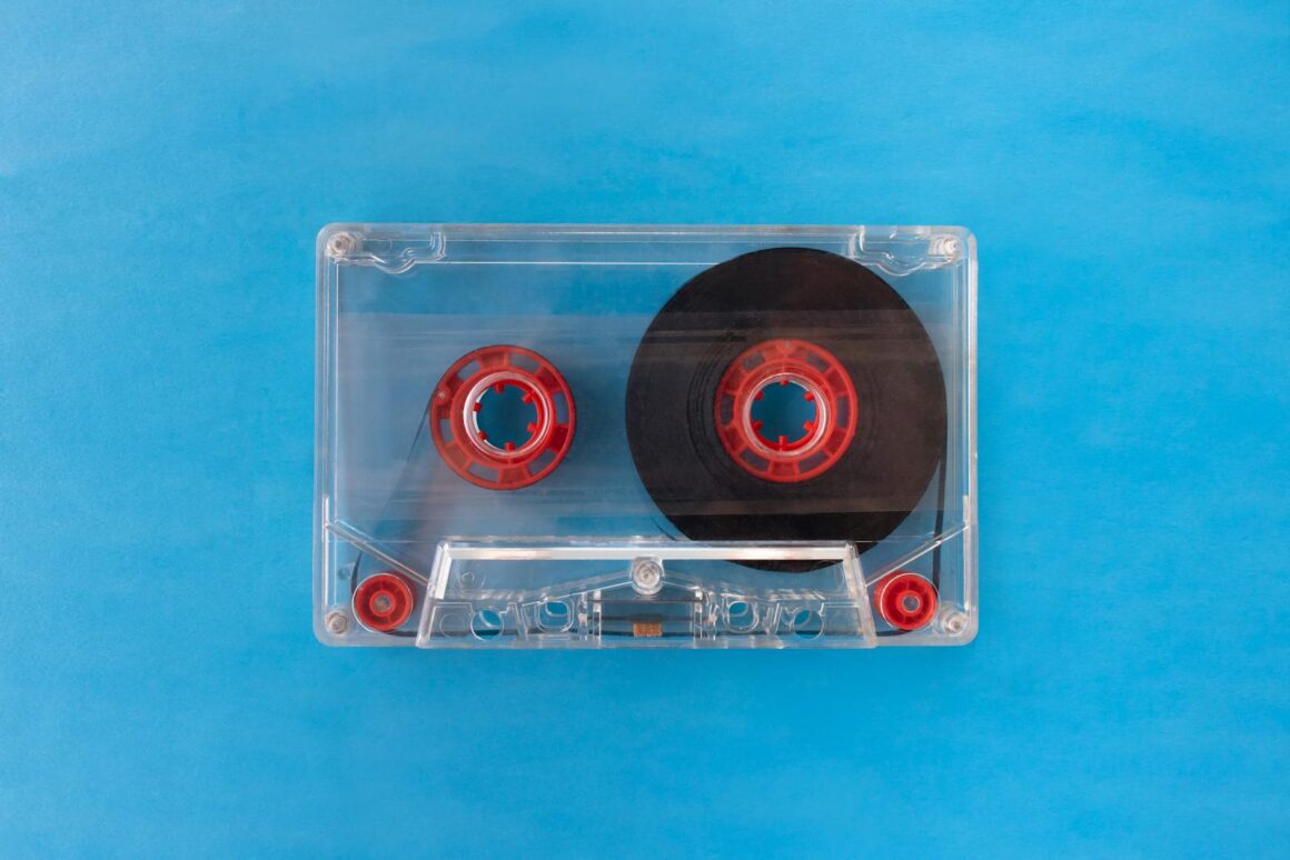 Vintage transparent cassette tape with red reels on a bright blue background.