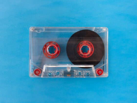 Vintage transparent cassette tape with red reels on a bright blue background.